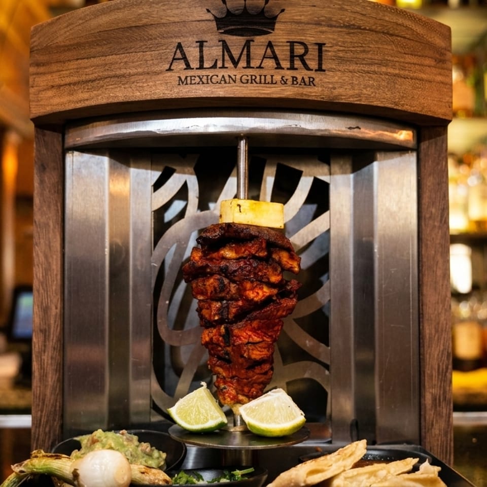 Almari Mexican Grill & Bar's al pastor trompo with pineapple, limes, guacamole, and tortillas.