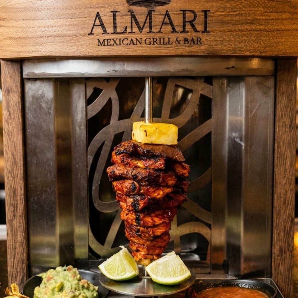 Almari Mexican Grill & Bar's al pastor trompo with pineapple, lime, guacamole, and salsa.